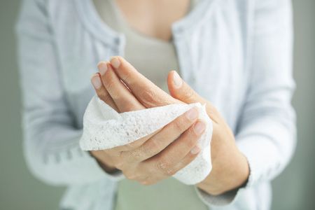 Frau reinigt Hände mit Kosmetiktuch