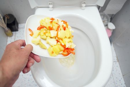 Teller mit Essen wird in Toilette geworfen