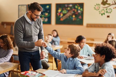 Lehrer klatscht mit Schüler im Plenum ab