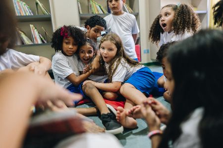 Mehrere Kinder sitzen gemeinsam auf dem Boden und spielen