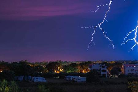 Two large and powerful lighting strikes crossing night blue sky