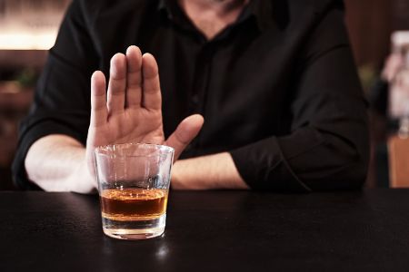 Mann lehnt Glas mit Alkohol ab