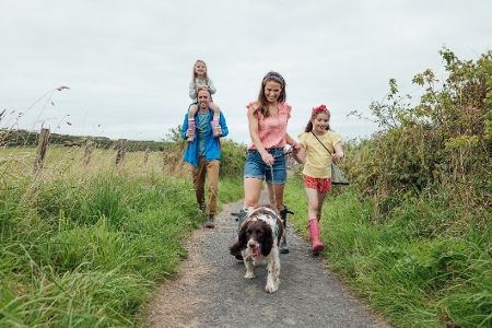 Familie mit Hund und zwei Kindern beim Spaziergang