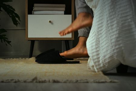 Zwei nackte Füße werden ins Bett gehoben