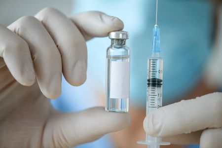 Arzt hält Spritze und Impfflüssigkeit in einer Ampulle