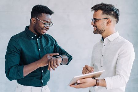 Zwei Männer unterhalten sich, einer schaut auf seine Uhr