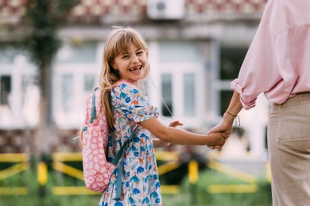 Kleines Mädchen an der Hand eines Erwachsenen lächelt