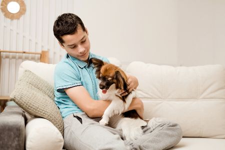 Junger Mann kuschelt mit Hund auf Sofa