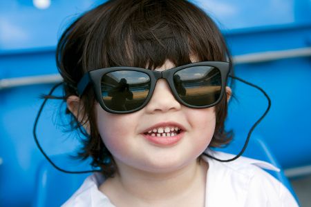 Kleiner Junge mit Sonnenbrille auf einer Tribüne