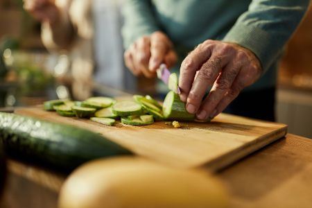 Ältere Person schneidet eine Gurke in Scheiben