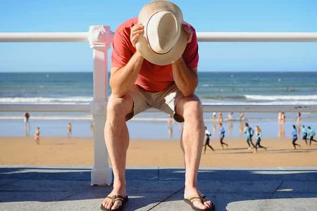Symbolbild: Mann sitzt frustriert am Strand