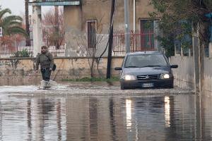 A man and a car try to cross a flooded road in Schiavonea, a