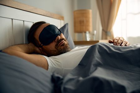 Mann mit Schlafmaske im Bett