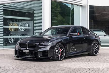 BMW M2 G87 von vorn vor einer Glasfront.