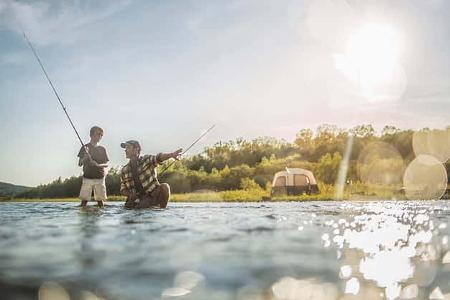 Caucasian father and son fishing in river
