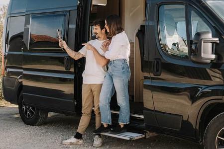 adult couple making a video call with their iPad in a camper van