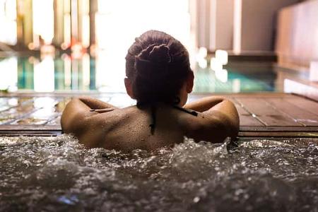 Woman relaxing in a hot tub pool during weekend days of relax and spa in a luxury place during travel vacations.