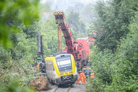 Mit einem Kran wird an der Unfallstelle, an der ein Regionalzug entgleist ist, gearbeitet. Ein Regionalexpress war am Sonntagabend (27.07.2025) in Riedlingen nach bisherigen Erkenntnissen infolge eines Hangrutsches entgleist.