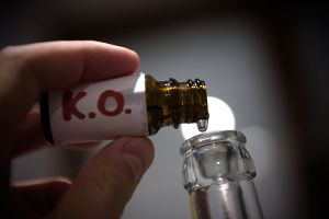 Mensch füllt aus Glasflakon K.o.-Tropfen in eine Flasche.