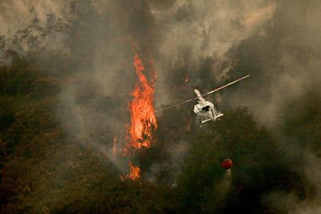 Ein Löschhubschrauber wirft Wasser über einem Feuer in der spanischen Provinz Ourense ab.