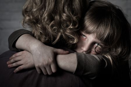 Kleines Mädchen mit verweinten Augen umarmt seine Mutter