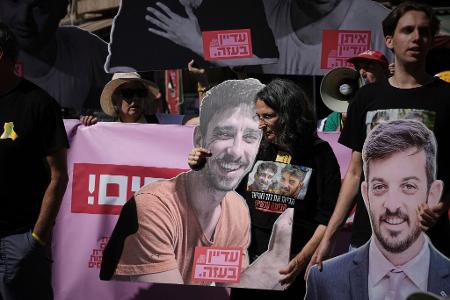 Demonstranten halten bei einem Protest gegen die Offensive in der Stadt Gaza Fotos von Geiseln. 