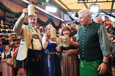 Bayerns Ministerpräsident Söder (l.) und Münchens OB Reiter (r.) stoßen mit ihren Ehefrauen auf eine friedliche Wiesn an.