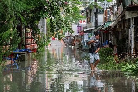 Ein Anwohner trägt in Hongkong ein Haustier durch das Hochwasser.