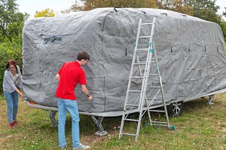 Die Schutzhülle wird von vorne nach hinten über den Caravan gezogen.
