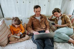 Father, mother and little daughter with gadgets sitting in the camper