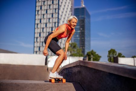 Ältere Frau fährt in urbaner Kulisse Skateboard