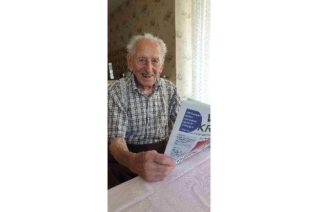 Karl Haidle sitzt an seinem 104. Geburtstag an einem Tisch und liest Zeitung.