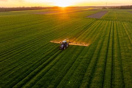 Ein Trecker sprüht auf einem Feld Insektizide aus