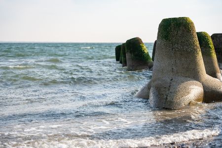 Betonwellenbrecher stehen am Strand im Wasser