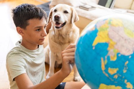 Junge sitzt mit seinem Hund vor einem Globus