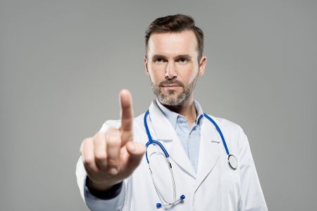 Arzt zeigt mit dem Zeigefinger Achtung