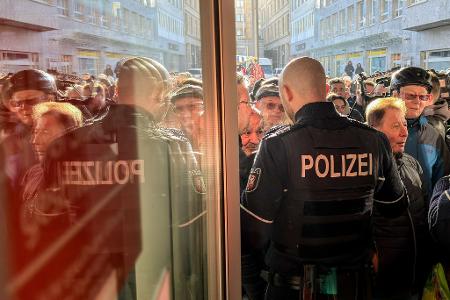 Polizisten sichern den Eingang der Sparkassenfiliale in Gelsenkirchen, vor der viele besorgte Kunde stehen und Informationen nach dem Einbruch in den Tresorraum verlangen.