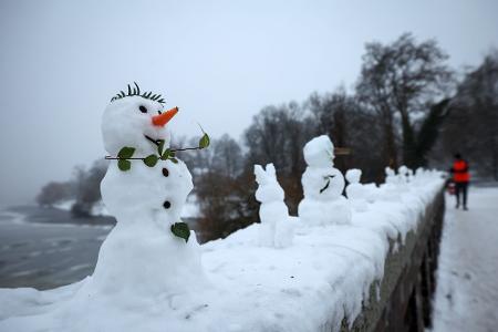 Eine ungewöhnliche Ausstellung: Zahlreiche kleine und winzige Schneefiguren stehen auf einer Mauer der Krugkoppelbrücke an der Alster im Hamburg.