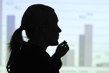 Hier erklärt eine Frau eine Statistik an der Wand - vielleicht eine Mutter, die sich bald um ihre Kinder kümmern muss? (Illustration)