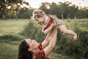 Frau hält Kleinkind in die Luft, das ihr ins Gesicht spuckt
