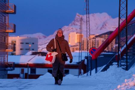 Eine Frau geht bei Sonnenuntergang auf einer Straße in Nuuk.