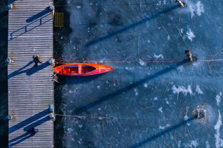 Ein kleines Paddelboot liegt am Anleger im Hafen an der Wismarbucht zwischen der Insel Poel und der Ostsee auf dem Eis. 