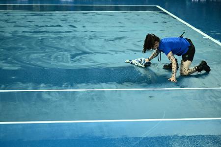  Australian Open: Eine Person trocknet den Platz mit einem Handtuch, nachdem das Spiel aufgrund des Regens unterbrochen wurde.