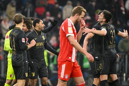 Fußball: Bundesliga, FC Bayern München - FC Augsburg, 19. Spieltag, Allianz Arena. Die Spieler des FC Augsburg jubeln nach Spielende. Davor geht Harry Kane (Bayern München). Das Spiel endete 1:2.