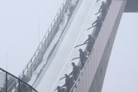 Zu viel des Guten: Mitarbeiter blasen beim Probedurchgang zur WM im Teamfliegen in Oberstdorf Schnee von der Flugschanze.