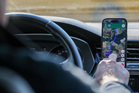 So ist es derzeit erlaubt: Das Handy steckt in der Halterung und wird nur kurz vom Fahrer beachtet. (Symbolbild)