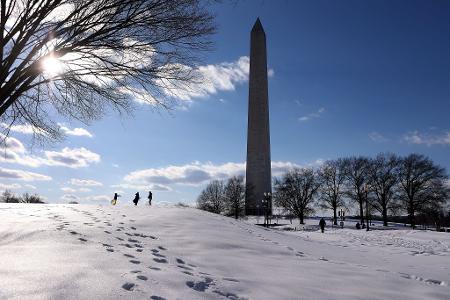Menschen spazieren im Schnee auf der National Mall.