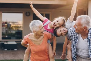 Großeltern mit ihren beiden Enkeln vor einem Haus