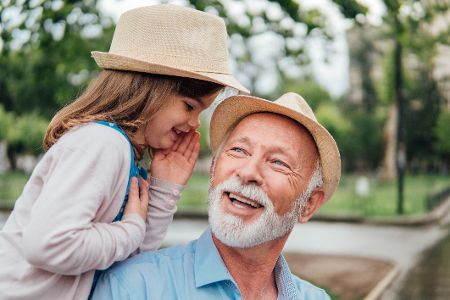 Enkelin flüstert ihrem Großvater etwas ins Ohr