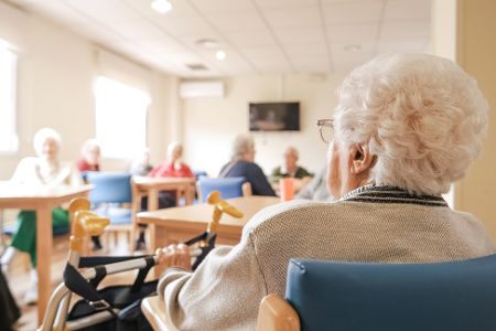 Mehrere Rentner sitzen in einem Raum im Pflegeheim zusammen
